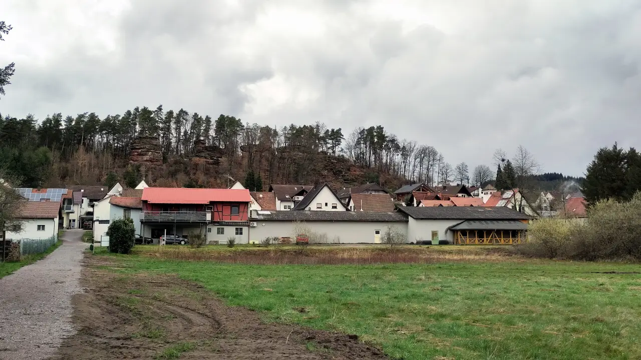 A few houses in front of an impressive sand stone rock face
