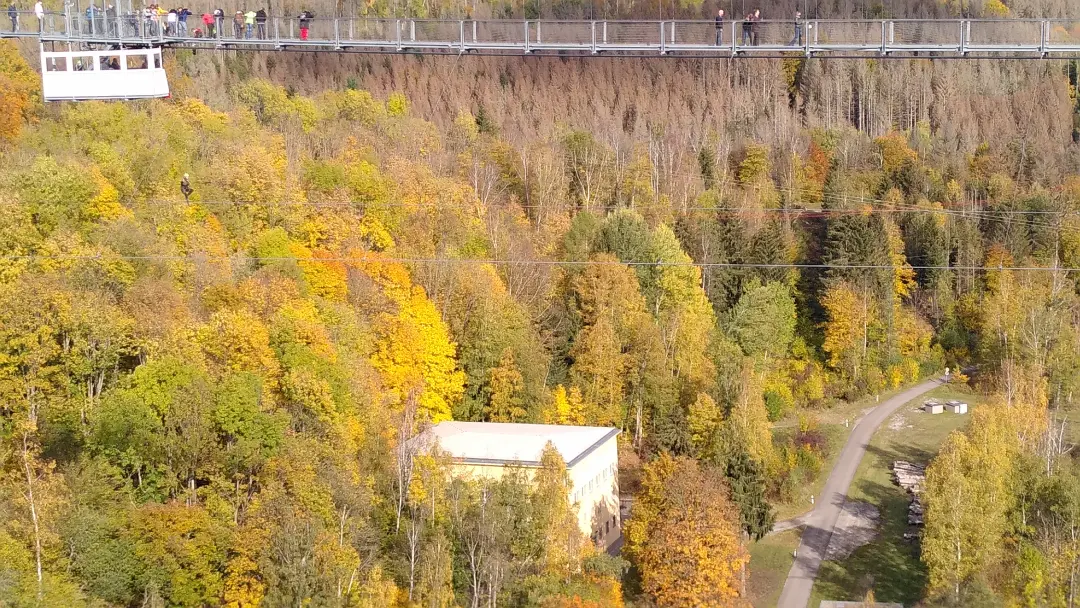 Close-up of the gondola below the pedestrian bridge where bungee jumping is possible. Below the gondola, someone is plunging downward on the bungee cord