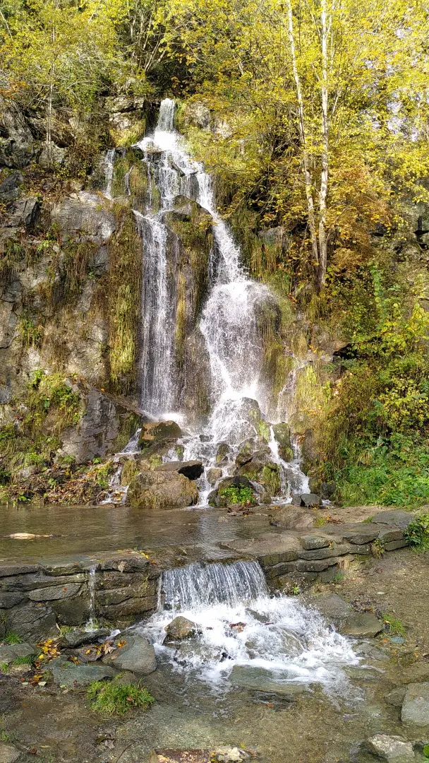 A small waterfall over some rocks into a small pond