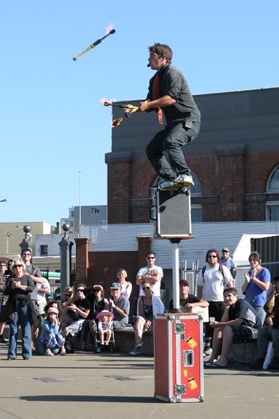 Ein Jongleur auf mehreren aufeinandergestapelten Kisten und einem Skateboard