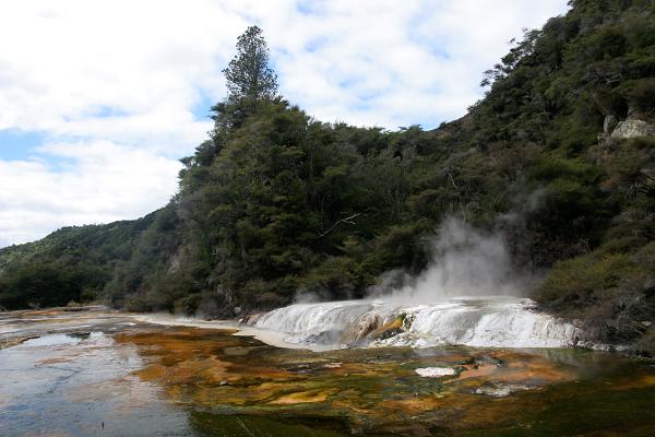 Eine farbenfrohe Terrasse aus abgelagerten Mineralien, über die Wasser in einen Bach fließt