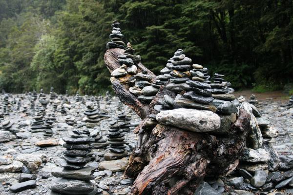 Aus Waschkieseln aufgestapelte Steintürme in einem Flussbett