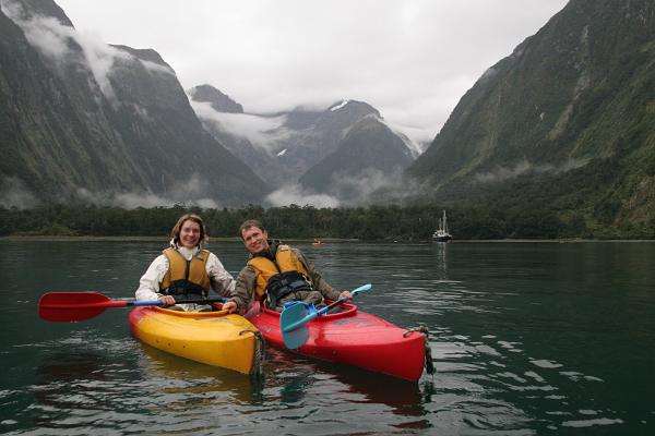Manu & Markus vor der beeindruckenden Kulisse des Milford Sound. Im Hintergrund hohe Berge.