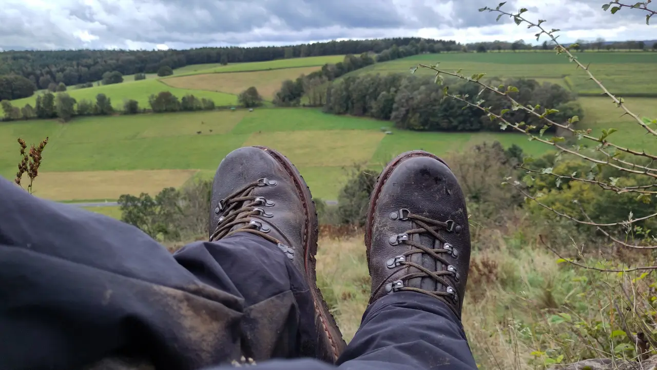 Großaufnahme meiner Wanderschuhe mit einem weiten Blick über das Tal von der Ruine Beilstein im Hintergrund