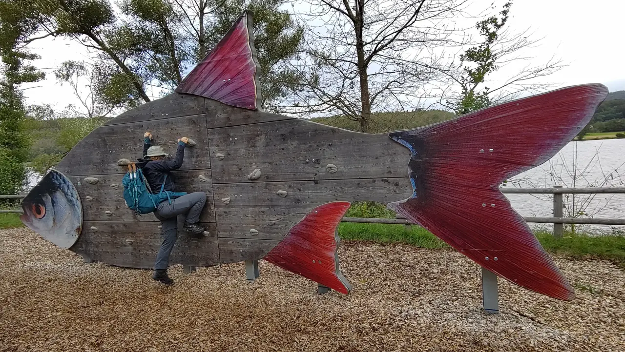 Manu versucht eine Kletterwand in Form eines riesigen Fischs zu erklimmen