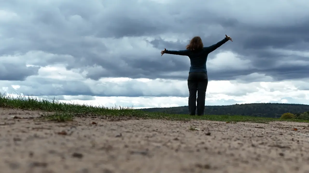Manu vom Boden aus vorm Himmel mit ausgestreckten Armen