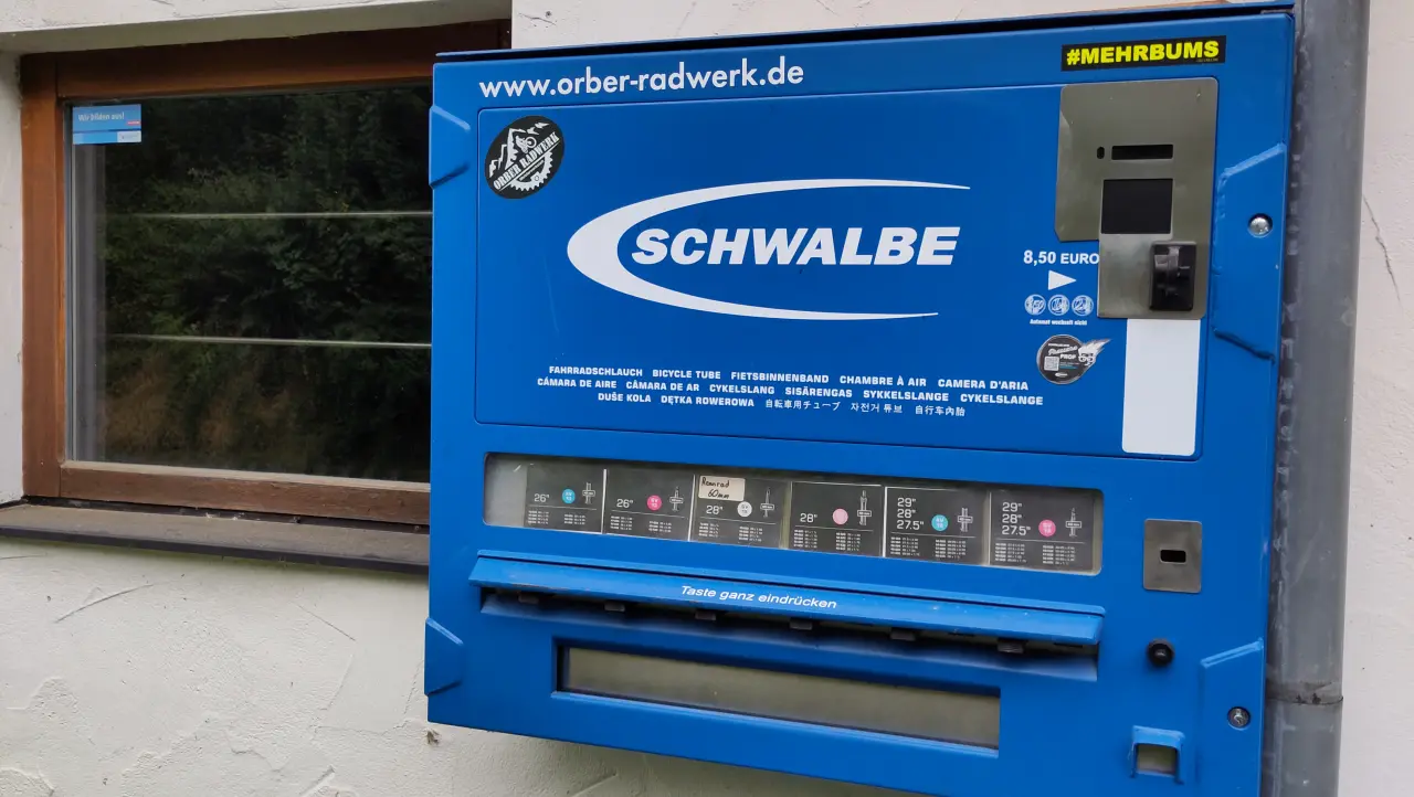 Ein blauer Automat der Firma Schwalbe, an dem man Schläuche für's Fahrrad kaufen kann. Oben rechts in der Ecke steht "#MEHRBUMS"